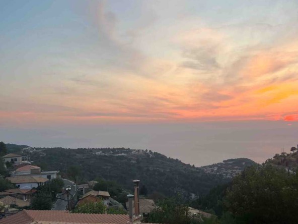 Breathtaking view of a quaint village and serene beach from the Exanthia Stone House, showcasing the property's idyllic location.