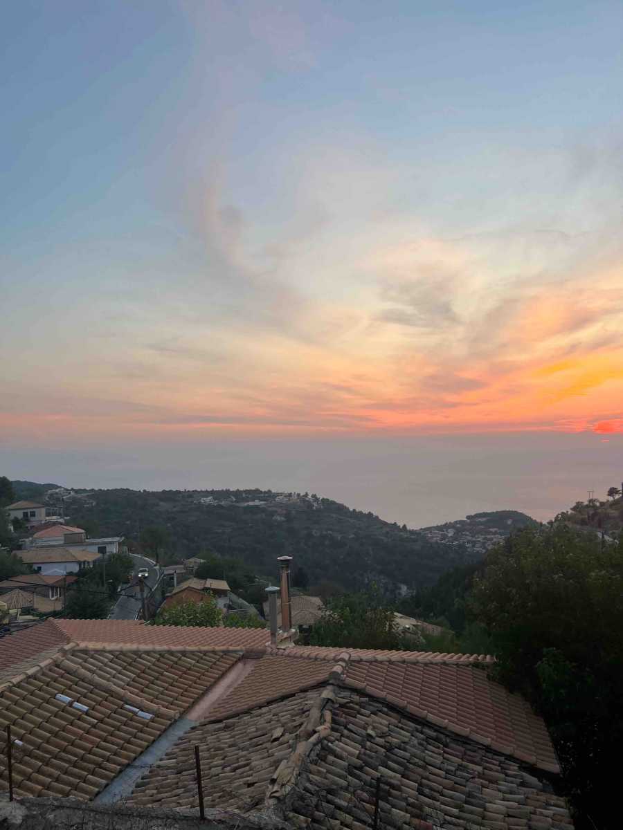 Breathtaking view of a quaint village and serene beach from the Exanthia Stone House, showcasing the property's idyllic location.