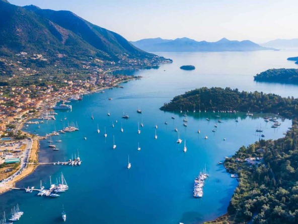 Scenic view of Nydri beach and surrounding mountains, one of the Best Areas to Buy Land in Lefkada.