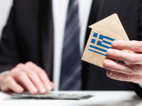 Man holding a model house in his hands, symbolising the first step in following our Guide To Buying Land In Lefkada