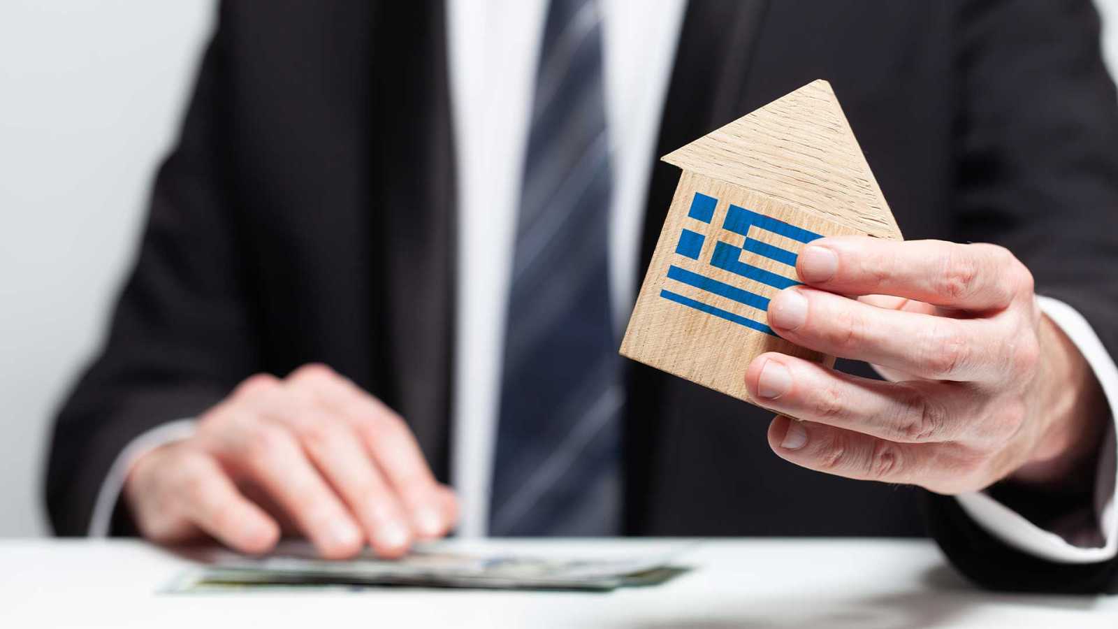 Man holding a model house in his hands, symbolising the first step in following our Guide To Buying Land In Lefkada