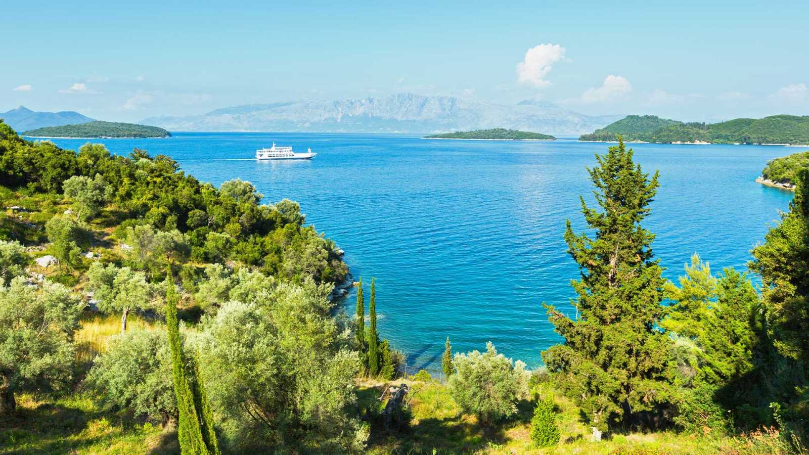 Beachfront land in Lefkada with lush trees and sandy beach, one of the Best Areas to Buy Land in Lefkada.